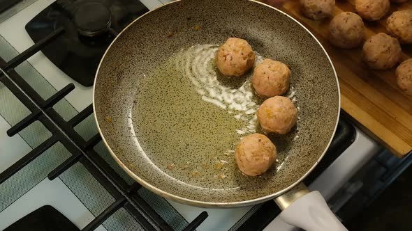 Woman's Hand Put Homemade Meatballs in Hot Oil on a Frying Pan