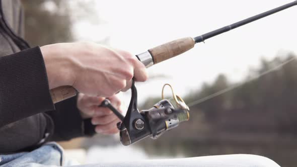 A young guy catches a predatory fish on spinning from the shore. Fishing as a hobby. alt