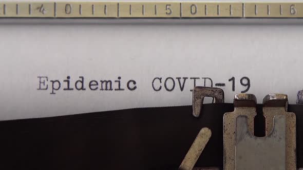 Typing phrase Epidemic COVID-19 on retro typewriter. Close up. alt