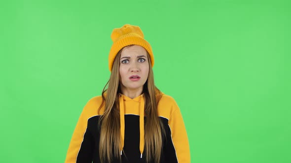 Portrait of Modern Girl in Yellow Hat Is Upset, Waving Her Hands in Indignation. Green Screen alt