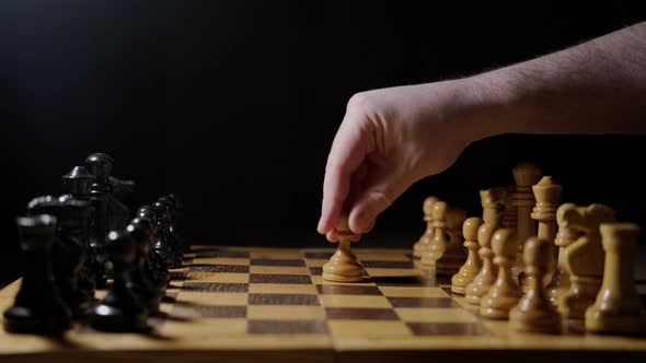 A man hand with a chess piece in a board game. Opening of the chess game with the move