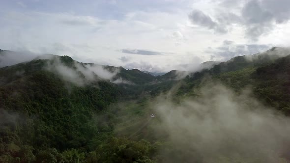 Aerial view flying thru the morning rain cloud covered tropical rain ...