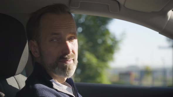 A Middleaged Handsome Caucasian Man Looks Around in Thought in a Car  Side Closeup