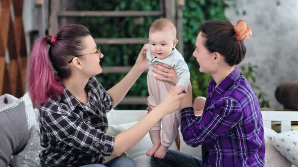 Same Sex Couple Family Smiling and Playing with Little Cute Baby at Home alt