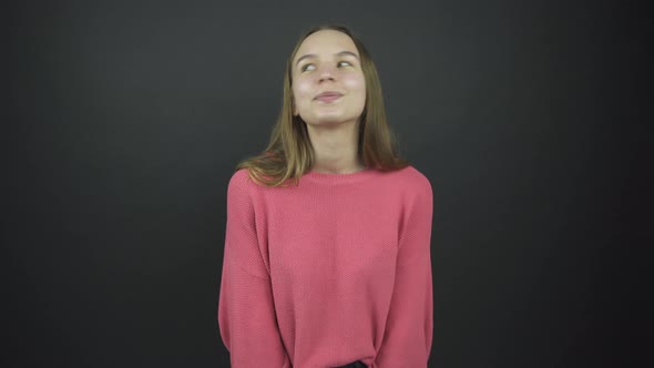 Beautiful Girl in Pink Pullover Stands with Enigmatic Smile alt