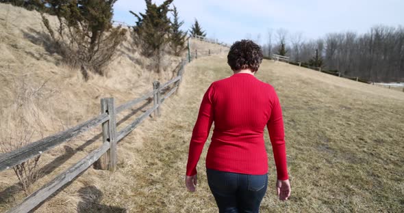 Woman in red top and jean walking. alt