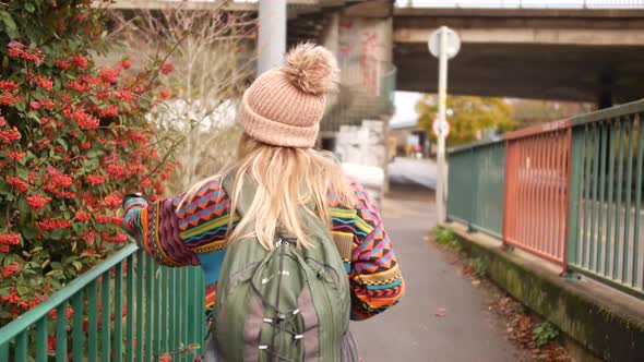 woman touching some berry bush as she walks by it and smiles into the camera afterwards alt