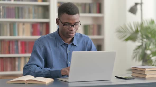 Young African Man Celebrating Success While Using Laptop in Office alt