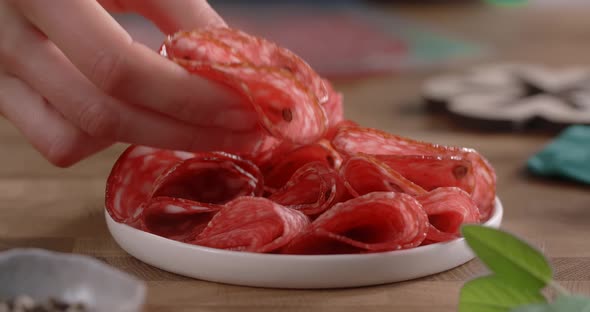 Woman Puts Sliced Salami to the Plate By Fingers in Slow Motion alt