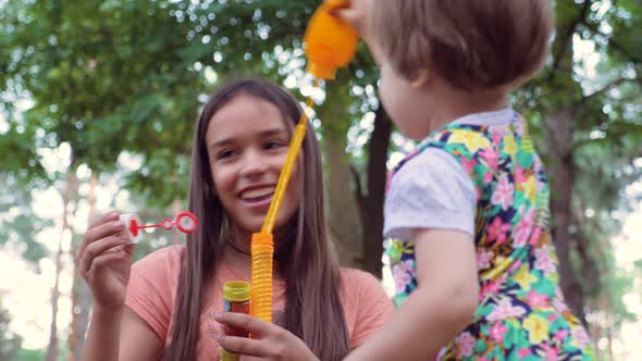 Older girl amuse, entertain little girl in the age of 2-3 years old. Games on fresh air alt