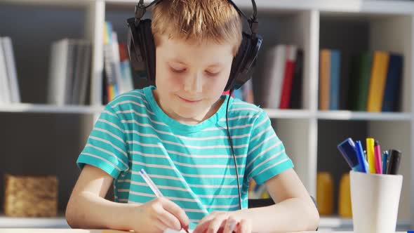 Boy is Doing  Homework at the Table. Cute Child is Learning at Home. alt