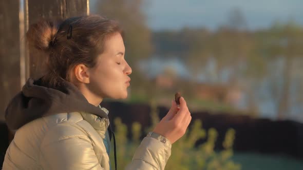 A Young Woman Enjoys a Chocolate Bar While Admiring the Sunset