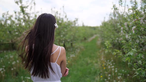 Brunette Female Walking Among Flowering Trees alt