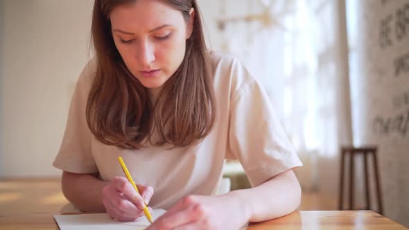 The Artist Drawing a Picture in a Cozy Interior with a Yellow Pencil
