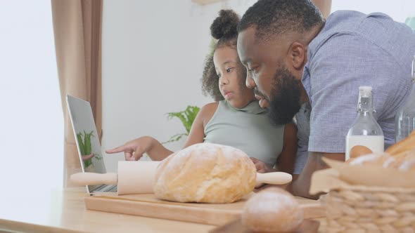 African America father and daughter learning recipe cooking online on laptop computer for cooking. alt