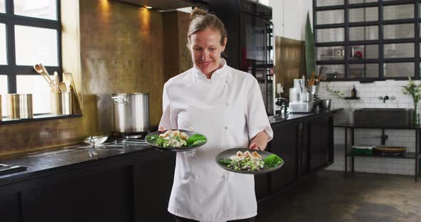 Caucasian female chef preparing a dish and smiling in a kitchen alt