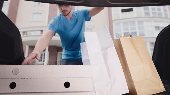 The Deliveryman Arrived at the Address and Picks Up the Order From the Trunk alt