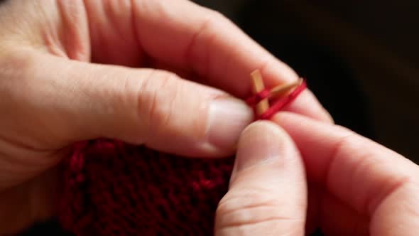 Knitting using wooden needles and burgundy yarn, close up