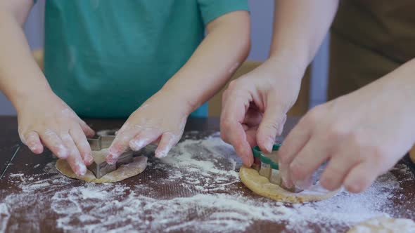 Little Child Hands and Mother Cutting Out Pastry Biscuits From Dough Together alt