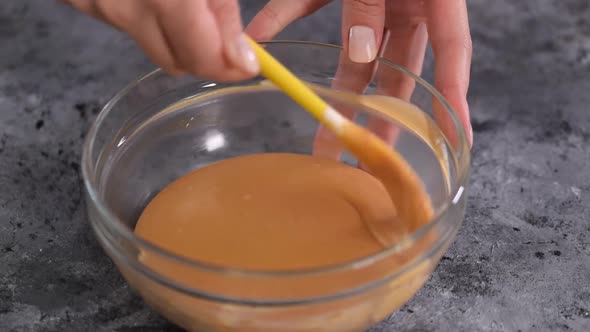 Pastry chef mixing a caramel mousse into glass bowl.