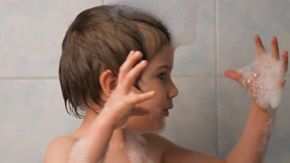 Boy Playing with Foam While Bathing. Facial Expression. A Child with Foam on His Head, Plays the