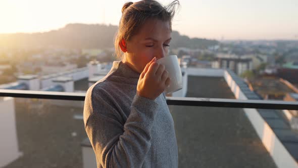 Woman Starts Her Day with a Cup of Tea or Coffee on the Balcony at Dawn Slow Motion alt