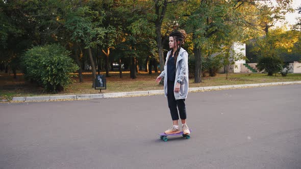 Pretty Young Woman with Dreadlocks Riding Skateboard in Park Slow Motion alt