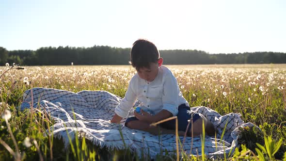 Boy Sits in a Field and Drinks Water From a Bottle Healthy Eating