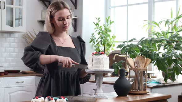 Pastry Chef Confectioner Young Caucasian Woman with Cake on Kitchen Table