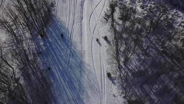 High Up Aerial View Of Snowmobile Traveling On Trail In Winter
