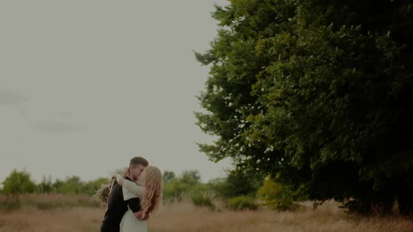 Girl Hugs Her Lover Holding a Bouquet of Wildflowers alt