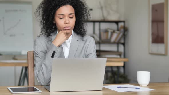 Pensive African Businesswoman Thinking and Working on Laptop alt