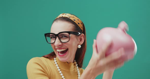 Funny sixties style woman shaking a money box checking her savings, looking very happy. Isolated.