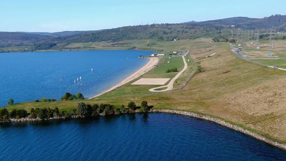 people enjoying the lake beach and its gardens, sailboats sailing on a sunny afternoon. Drone shooti alt