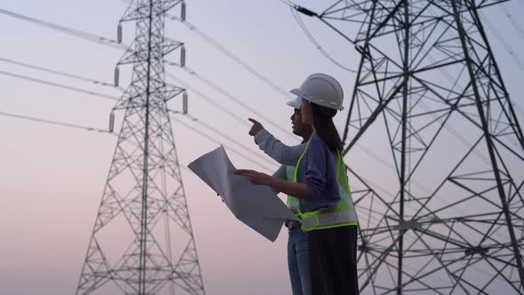 Two specialist electrical engineer working near to High voltage tower.