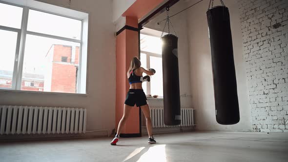 Female Athlete Boxing the Punching Bag in Urban Industrial Gym