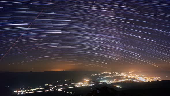 Star Trails In Night Sky. Illuminated night city under the stars, 4K alt
