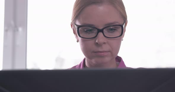 Portrait of Smiling Woman Wearing Glasses Working on a Laptop