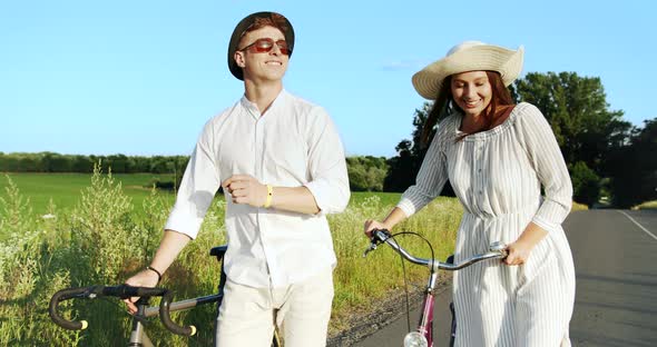 Couple Walking with Bicycles on Field Road