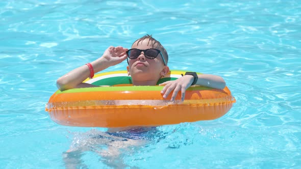 Happy Child Boy Swimming on Inflatable Circle in Swimming Pool on Sunny Summer Day During Tropical alt