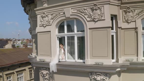 Bride in Boudoir Dress Sitting on Window Sill Wedding Morning Preparations Woman in Night Gown Veil alt