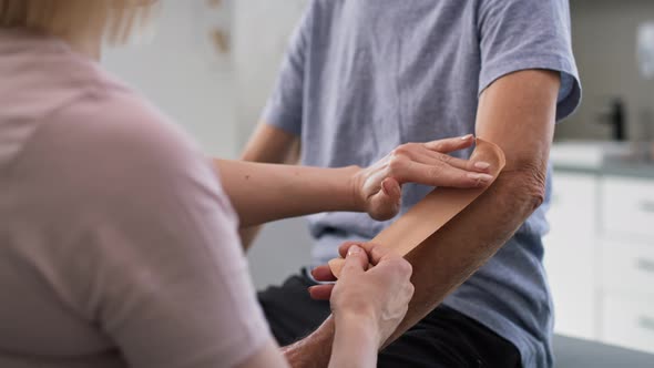 Physical therapist applying kinesio tape on patient's arm. Shot with RED helium camera in 8K. alt