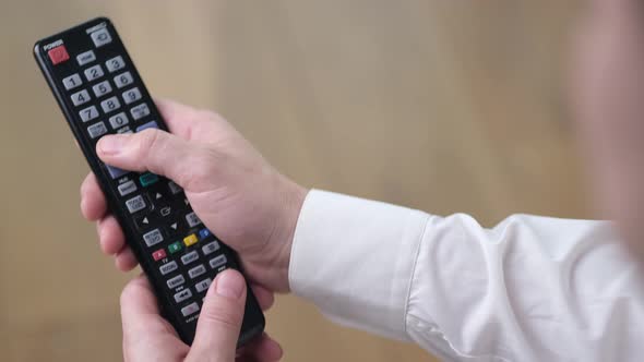 A person watches a smart TV and uses a modern black remote control. Close Up. 4k alt