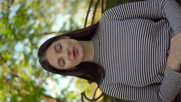 Young Woman Talking to Camera Video Chat Sitting on Bench in Park Vertical Video