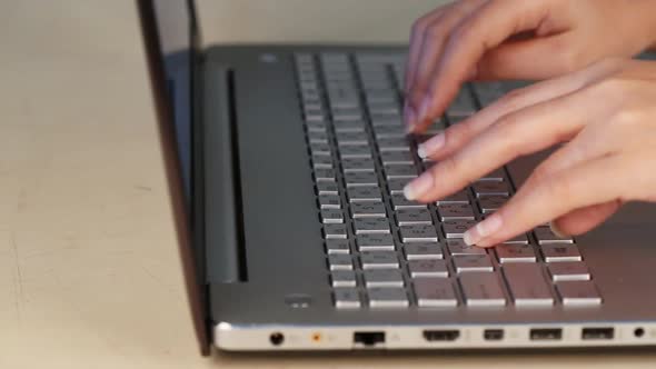 panning shot of hands typing on a laptop keyboard