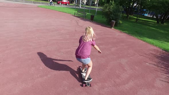 Cheerful blonde woman riding on a longboard alt