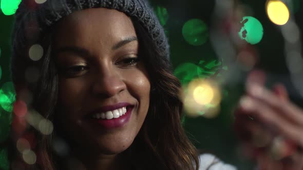 Young woman reaching out and touching holiday lights alt