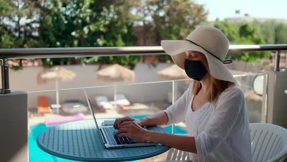 Lady in Mask Talks Online Using Laptop in Hotel on Vacation at COVID-19 Pandemic