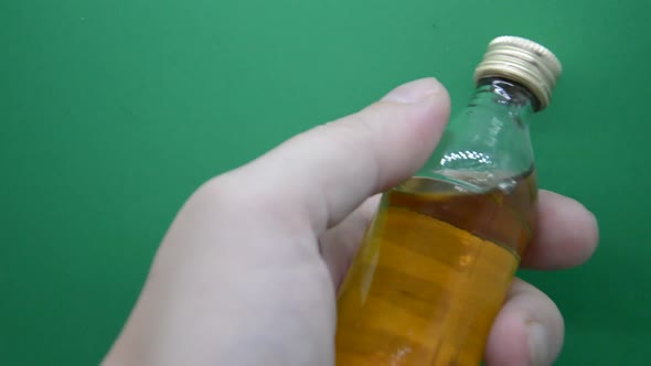 Man holds and twirls a bottle of strong alcohol in his hand