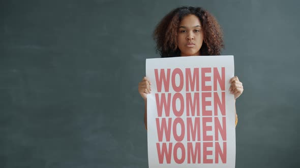 Portrait of Independent AfroAmerican Lady Standing with Women Empowerment Banner on Black Background alt